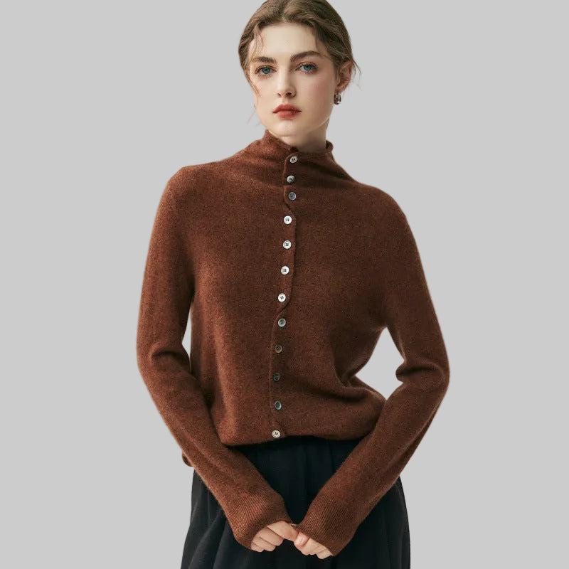 A woman wearing a brown fuzzy mock-neck button-up sweater with long sleeves and dark pants, standing against a light gray studio background.