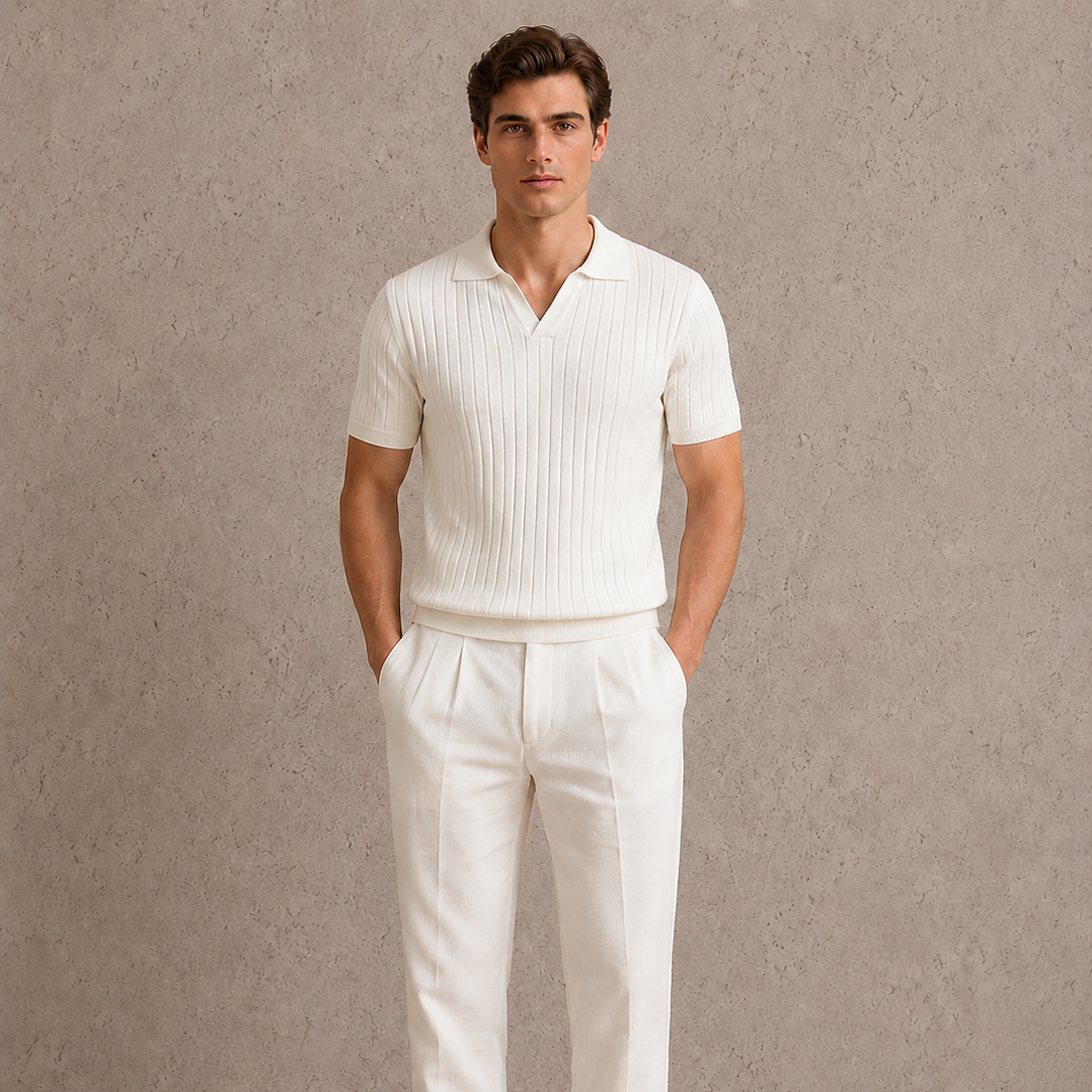 Man wearing a white ribbed polo shirt and white pants against a neutral background