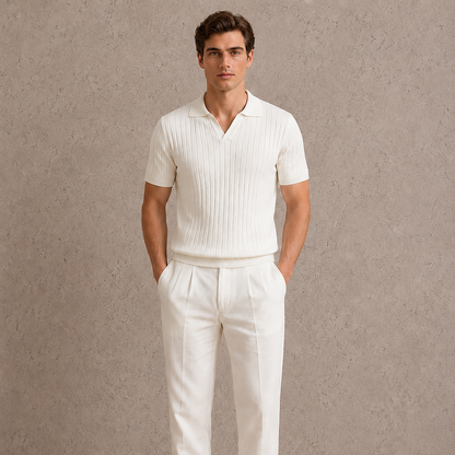 Man wearing a white ribbed polo shirt and white pants against a neutral background