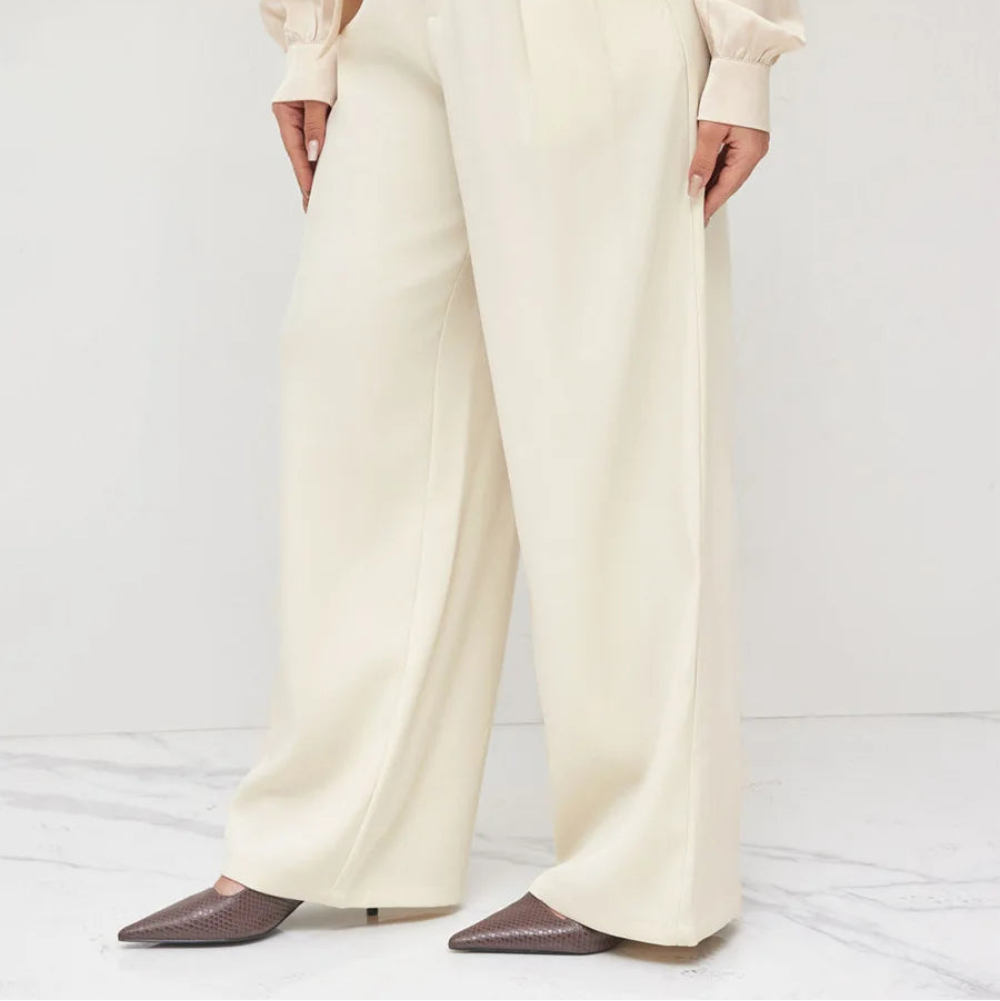 Person wearing a beige blouse and cream wide-leg pants on a white background