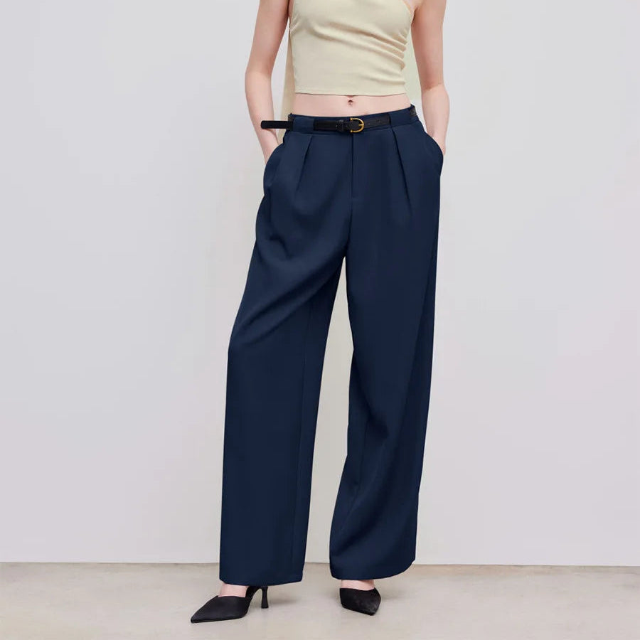 Woman wearing a light green halter top and navy wide-leg pants against a white background
