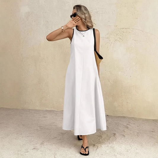 Woman wearing a white sleeveless dress against a beige wall.