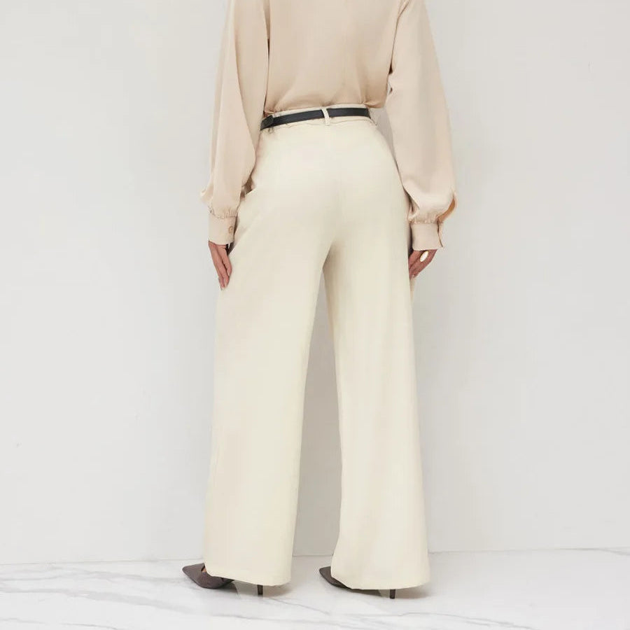 Person wearing a beige blouse and cream pants on a white background